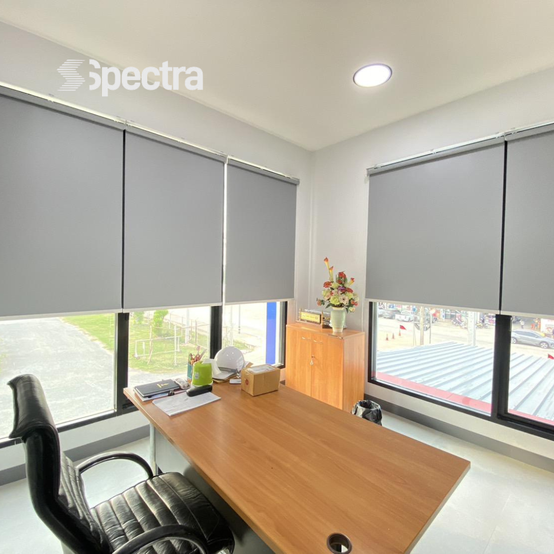 Grey roller blinds installed in an office workspace